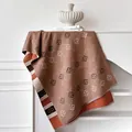 Detail van gebreide bloemensjaal met koffie patronen en zachte franje aan de rand - camel