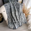 Châle pashmina bleu à motif jacquard paisley avec franges drapé sur une chaise - Gris