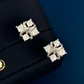 Κοντινό πλάνο από ασημένια σκουλαρίκια 18K με τέσσερα λαμπερά ζιργκόν σε σχέδιο χιαστί - Επιπλατινωμένα σκουλαρίκια καρφωτά
