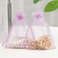 Purple organza drawstring gift pouch with jewelry inside on a minimalist background - Violet