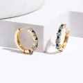 Golden huggie hoops with blue and clear zircon inlay on white geometric stone props - Gold+Blue Zirconia
