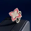 Macro shot of silver ring with red petals and diamond clover detail on dark base - Silver Pink Chalcedony Style