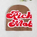 Close-up of jacquard knit beanie with red and white Rich Mob lettering on brown fabric - Camel