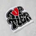 Detail of white Y2K beanie featuring black graffiti text and red stitched heart design - White