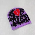 Flat lay of purple Y2K beanie with black TOP TIER text and red broken heart pattern - Dark Violet