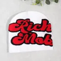 White knit beanie featuring bold red and black Rich Mob lettering on a textured surface - White