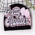 Black knit beanie with Pretty Hustler text and pink butterfly pattern for winter - One Size / Black