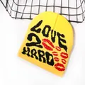 Yellow knitted beanie with black LOVE TO HARD letters and red lip patterns in street style - One Size / Yellow