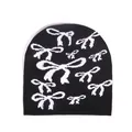 Fashionable black knitted beanie featuring white bow patterns on a clean white background - One Size / Black
