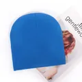 Bright blue acrylic knit beanie for winter alongside a fashion magazine on white - Teal