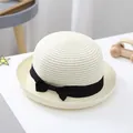 Detail of kids beige straw hat featuring a black ribbon bow and fine woven texture - S (52-54cm) / Cream