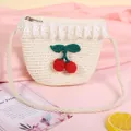 Dettaglio borsa di paglia per bambini con pizzo e ciondoli a ciliegia su tessuto rosa - Bianco