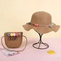 Vista detallada del conjunto de sombrero de paja y bolso infantil con pompones - Sombrero / Café