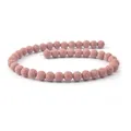 Dettaglio macro di perle di pietra lavica rosa naturale con finitura opaca testurizzata - 4mm / Rosa (N. 5)