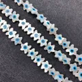 Macro shot of white star-shaped mother of pearl beads with blue evil eye pattern - Starfish Shape / Large