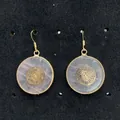 Detail van rozenkwarts oorbellen met gouden geometrische inleg en gepolijste metalen haken - Meanderpatroon Stijl