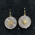 Detailweergave van rozenkwarts oorbellen met gouden mandala-patroon op zwarte basis - Mandala Stijl