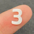Weiße Naturmuschel-Perle in Form der Nummer drei für DIY-Schmuck auf der Fingerspitze - Zahl 3 / 10mm