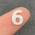 Weiße Süßwassermuschelperle in Form der Nummer 6 für Schmuck auf einer Fingerspitze - Zahl 6 / 10mm