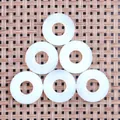 Nahaufnahme von sechs weißen Edelsteinanhängern in Donut-Form auf gewebter Matte - 20mm / Opal