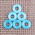 Detail von sechs blauen, lichtdurchlässigen Donut-Edelsteinanhängern auf Webgrund - 20mm / Aquamarin