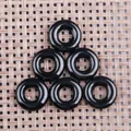 Detailansicht von sechs schwarzen Obsidian-Donut-Anhängern auf gewebtem Grund - 20mm / Schwarzer Achat