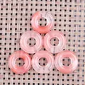 Sechs rosa gestreifte Edelstein-Donut-Anhänger auf einer gewebten Bambusmatte - 20mm / Wassermelonen Quarz