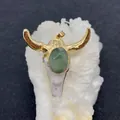 Dettaglio del ciondolo a testa di toro con gemma verde e corna dorate su pietra - Stile Pietra Verde (5)
