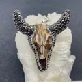 Primo piano di un ciondolo a teschio di toro dorato con strass su cristallo - No. 1 (Texture Bianco Latte)