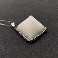 Detail view of a white pyramid gemstone pendant with rhinestone inlay and silver clasp - White Jade