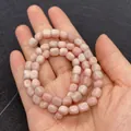 Strand of natural pink opal cube beads for DIY jewelry making held in hand - 5X7mm / No. 16 (Pale Pink Natural Stone Texture)