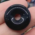 Polished natural black agate donut pendant held by hand showing smooth glossy finish - Black Agate