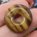 Polished natural tiger eye stone donut pendant featuring a golden brown chatoyancy finish - Tiger's Eye