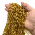 Filo di perline sfaccettate in pietra color ambra tenuto in mano per gioielli DIY - Pietra Gialla Tinta
