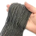 Filo di perle di pirite sfaccettate con lustro metallico, tenuto in mano per la scala - Ematite