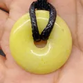 Tiger Eye Stone 20mm donut pendant with black braided cord held in hand - Topaz
