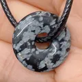 Pendentif donut en obsidienne flocon de neige sur cordon noir présenté dans la paume - Obsidienne flocon de neige