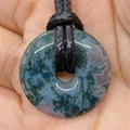 Natural green moss agate donut pendant with black braided cord shown in palm - Moss Agate (9)