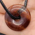 Pendentif donut en pierre naturelle brun-rouge avec cordon noir tressé sur main - Obsidienne Acajou