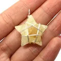 Star shaped yellow crystal pendant with silver wire wrap held in hand for scale - 15x35mm