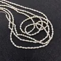 Vue détaillée de perles d'eau douce blanches de 2-3mm en forme de riz sur fond noir - Taille micro