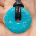 Blue turquoise donut pendant with black cord held in hand showing natural texture - Sky Blue Mottle Stone (No.19)
