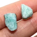 Macro di orecchini a perno con pietre grezze naturali blu cielo tenuti sul polpastrello - Amazzonite