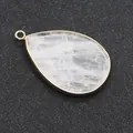 Pendentif goutte en amazonite avec bord doré sur une surface noire texturée - Cristal blanc