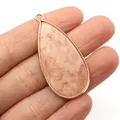 Pink marbled water drop stone pendant with gold metal rim held by a hand - Pink Orange Marble Style (No. 11)