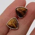 Pendientes triangulares de ojo de tigre dorados mostrados en el dedo como guía de talla - Ojo de tigre