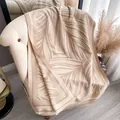 Dettaglio ravvicinato dello scialle in maglia beige con motivo a foglie e frange fini - Stile Lungo / Cachi
