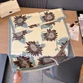 Detalle de bufanda de jacquard con girasoles y bordes de flecos sobre mesa de madera - Azul claro