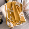 Ginger yellow cashmere scarf with white floral patterns draped on a sofa - Yellow