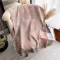 Knit zebra pattern scarf in beige, taupe and soft pink with fringe on a chair - Khaki